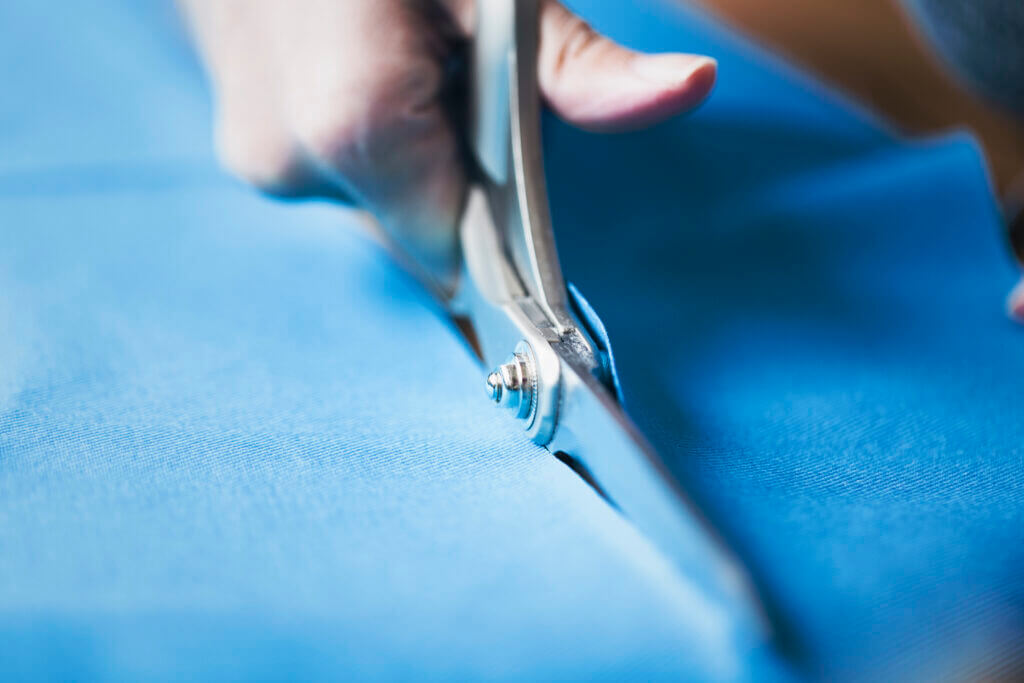 Hands of woman cutting blue fabric