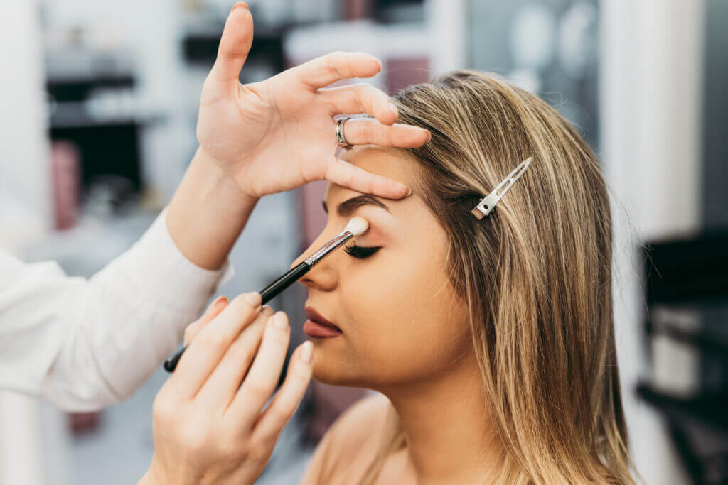 Professional makeup artist doing professional make up of young woman.