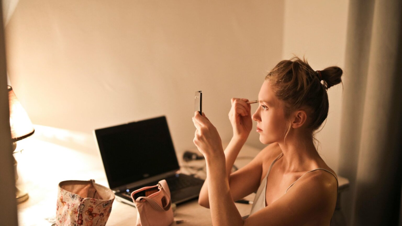 Woman applying makeup in front of mirror