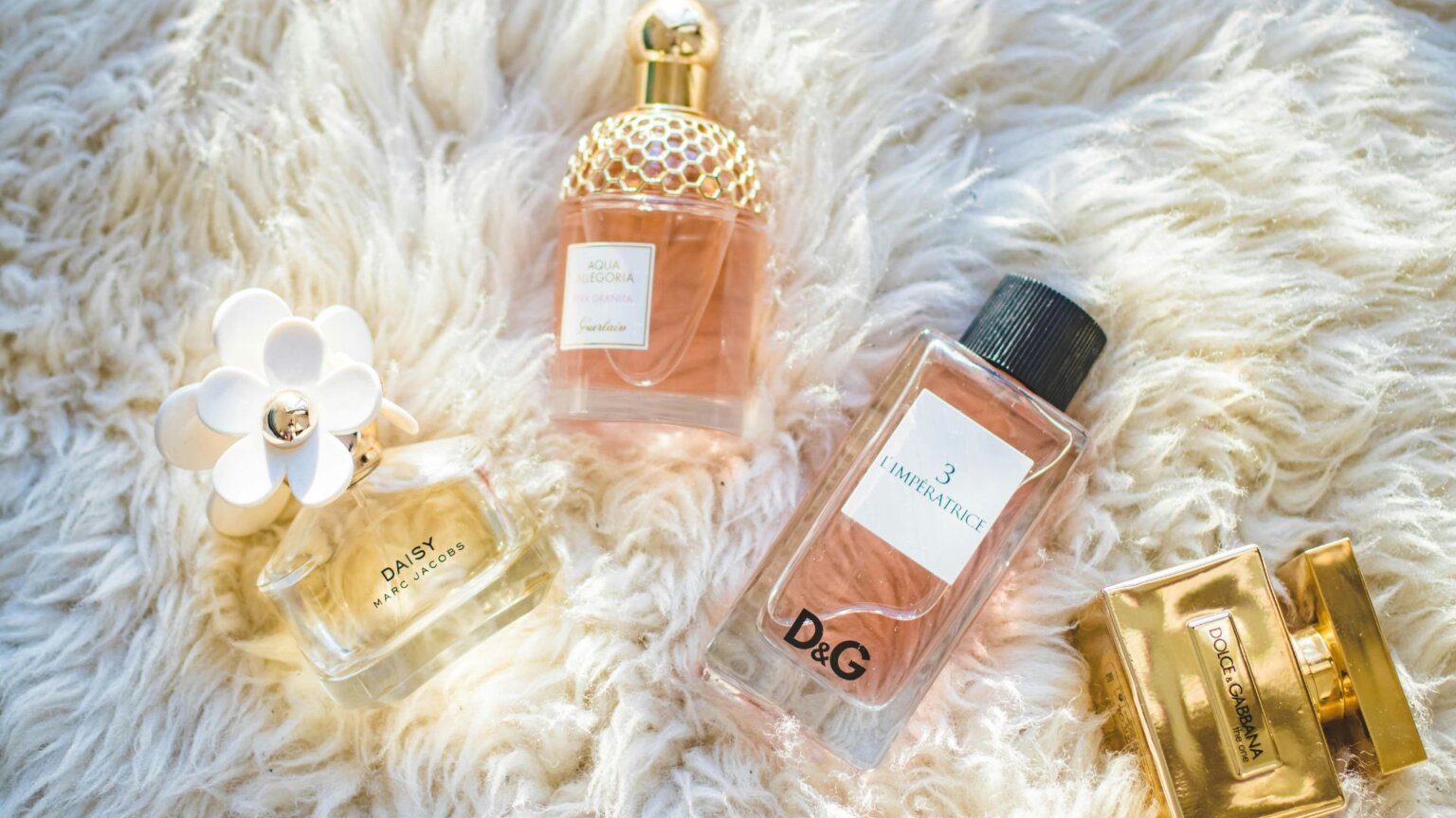 Four assorted glass perfume bottles on a reflective surface