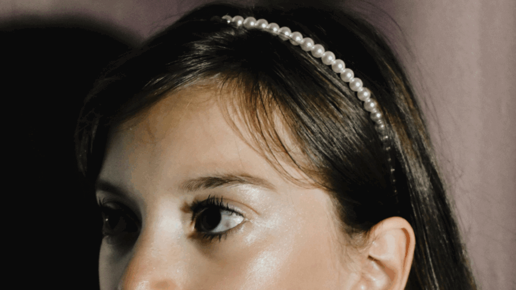 Young girl wearing a narrow headband and pearl earrings, gazing thoughtfully