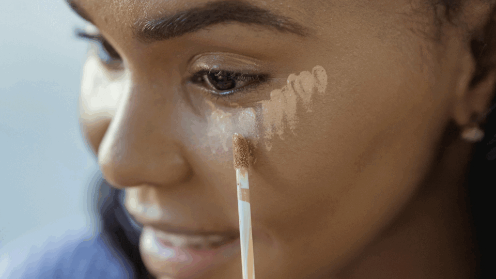 Woman applying concealer under her eyes using a makeup sponge