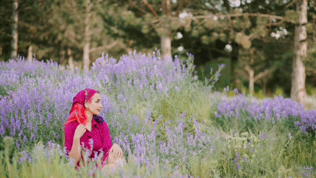 Woman in a meadow wearing a patterned scarf and looking into the distance