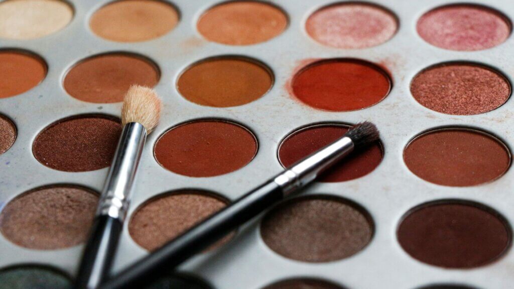 Black-handled makeup brush resting on neutral-colored powder