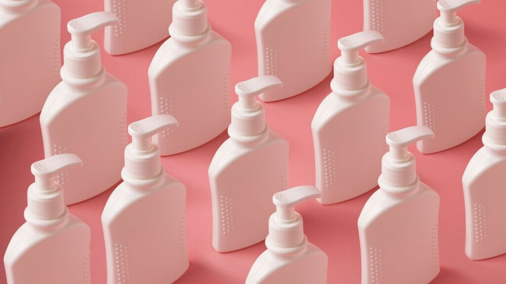 Liquid soap bottles on pink background, creative pattern with soap containers