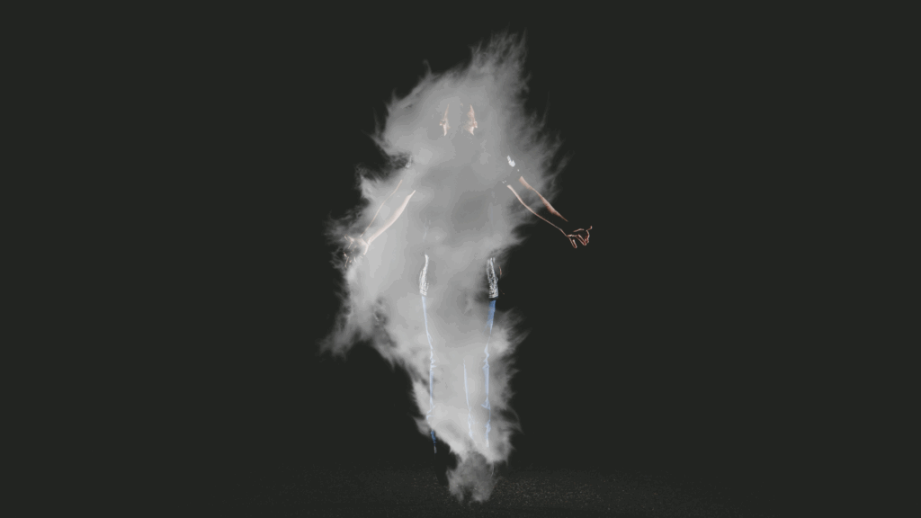 Person standing near swirling smoke in dark background