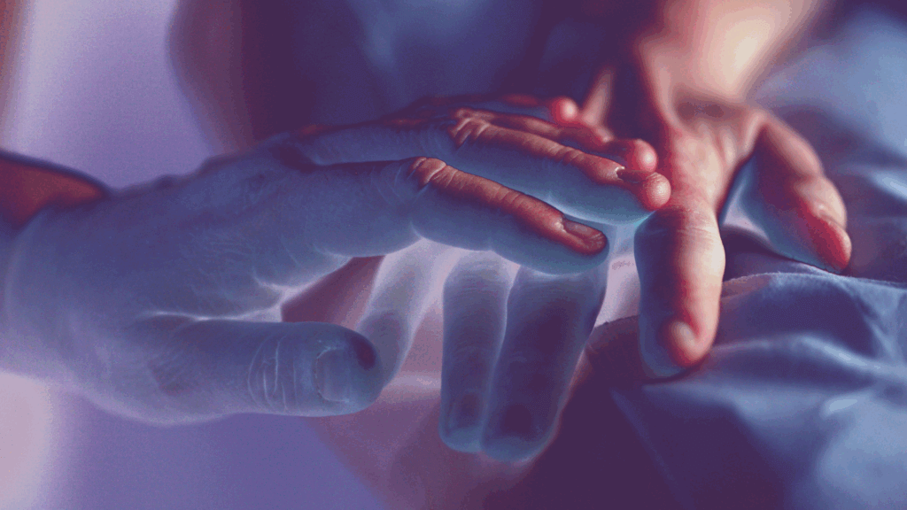 Person’s hands reaching outward in dim lighting