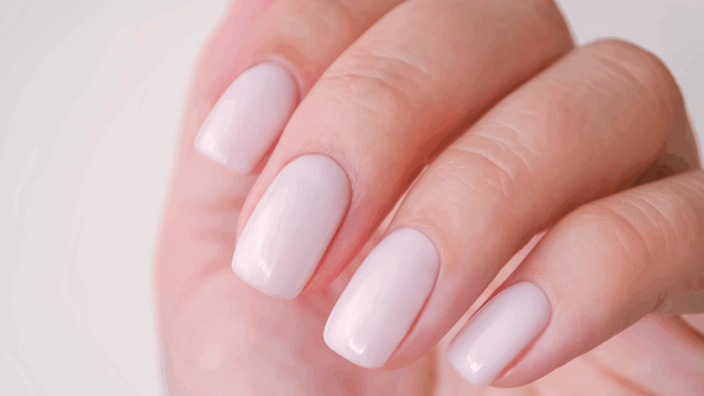 Young woman’s hand with pearly white manicure against white background