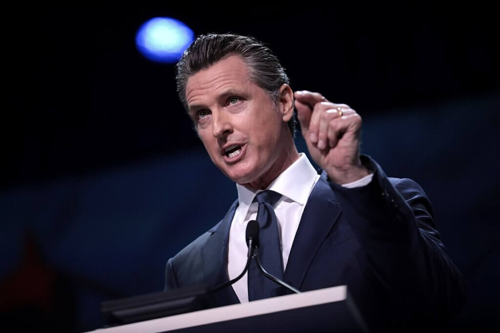California Governor Gavin Newsom speaking at a podium and gesturing during an address.