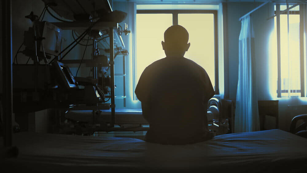 Siluete of a person staring at window at the hospital bed.