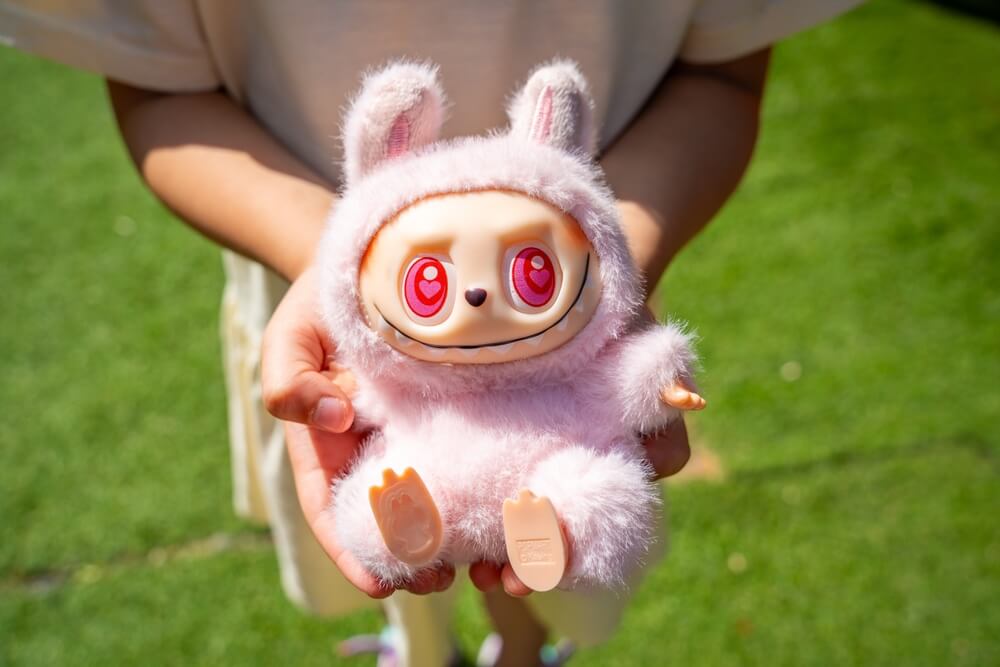 Budva, Montenegro - June 12, 2025: Close-up of pink Dada figure from Pop Mart LaBubu collection in child hands. Focus on popular collectible toy and emotional connection through play.