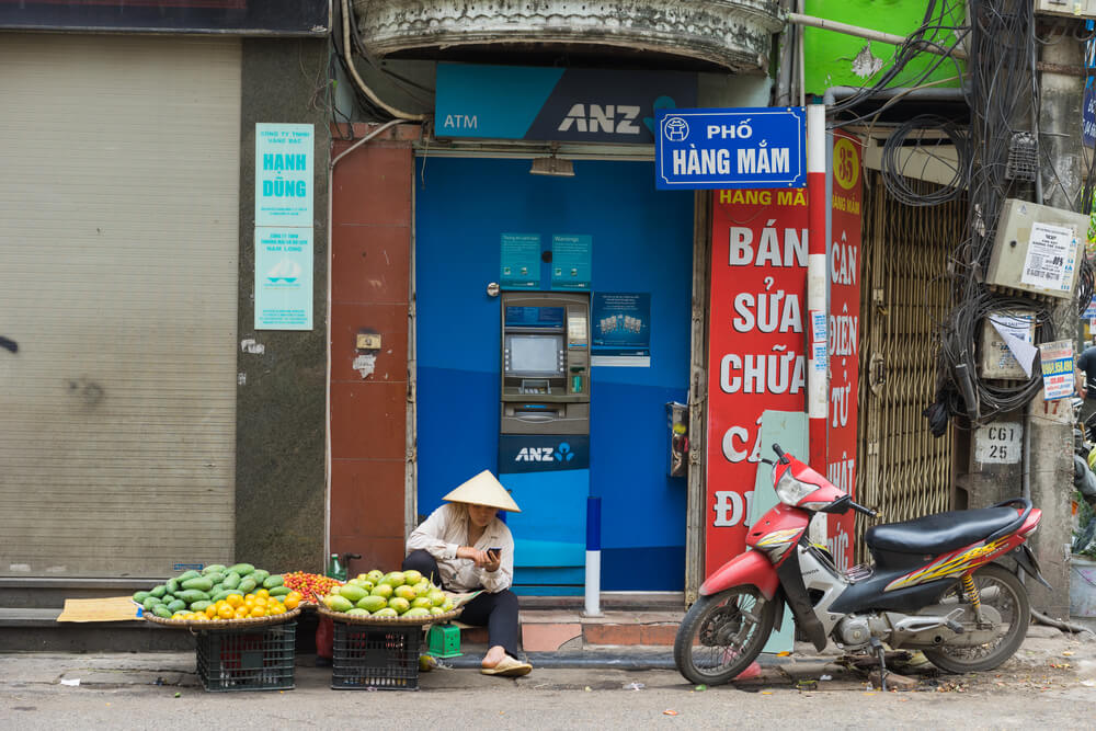 Hanoi, Vietnam - Apr 5, 2015: Vendor sales fruit in front of ANZ ATM in Hang Mam street, Hanoi