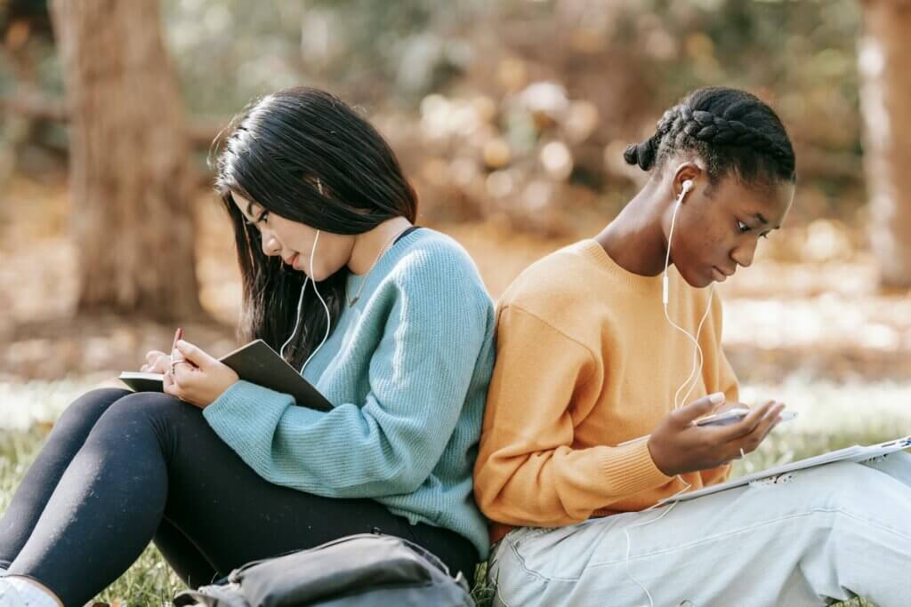 Two students sitting back to back on a lawn