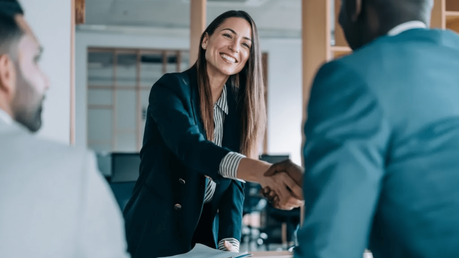 A woman shaking a mans hand in an office setting