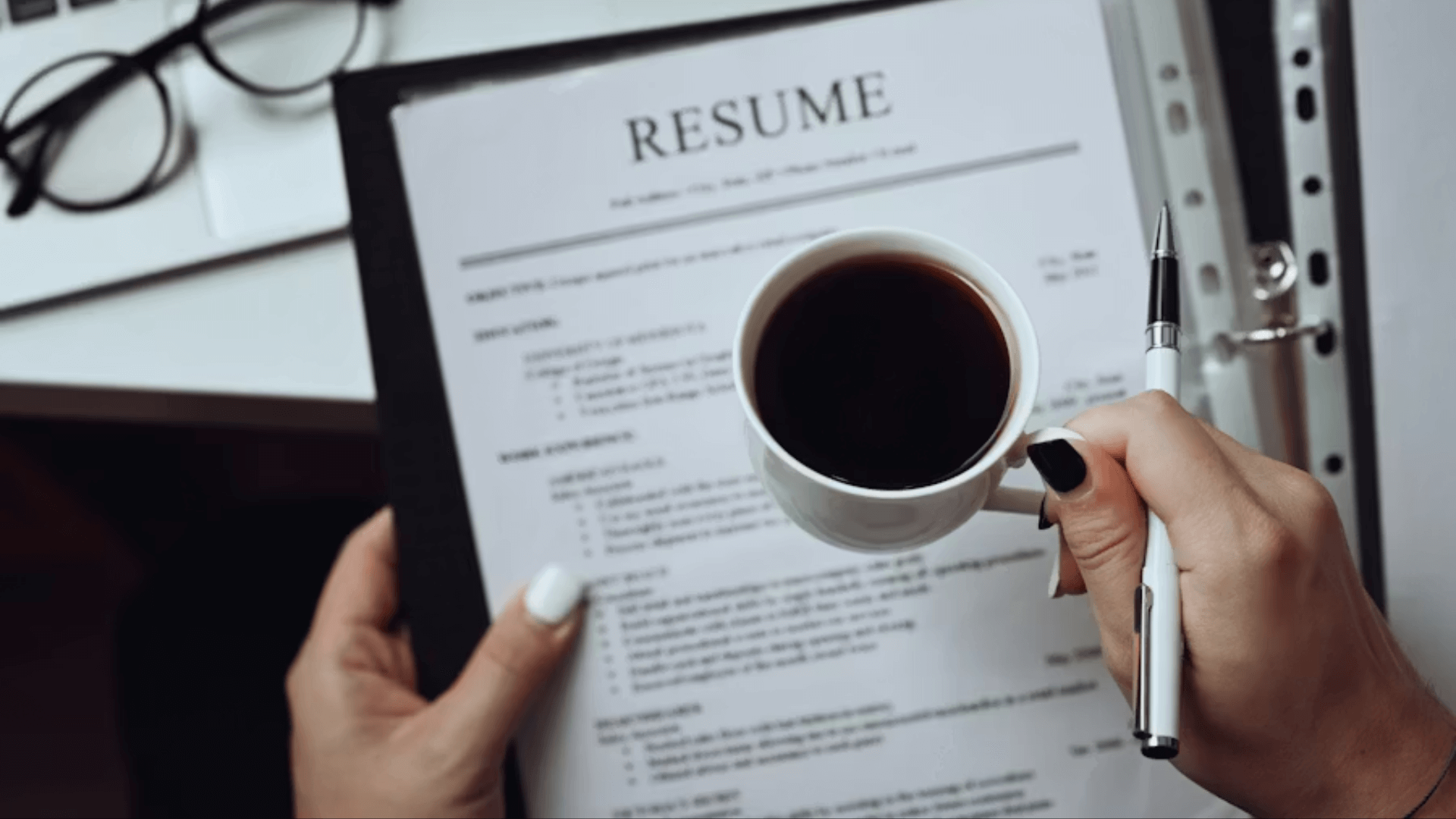 A resume on a clip board with a cup of coffee in front of it