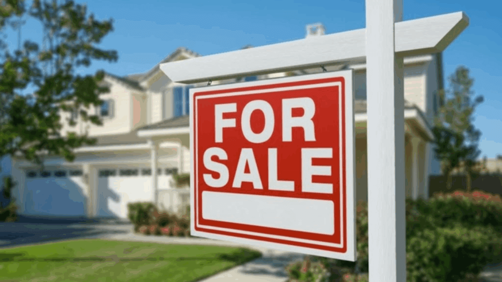 A red for sale sign sits in front of a house