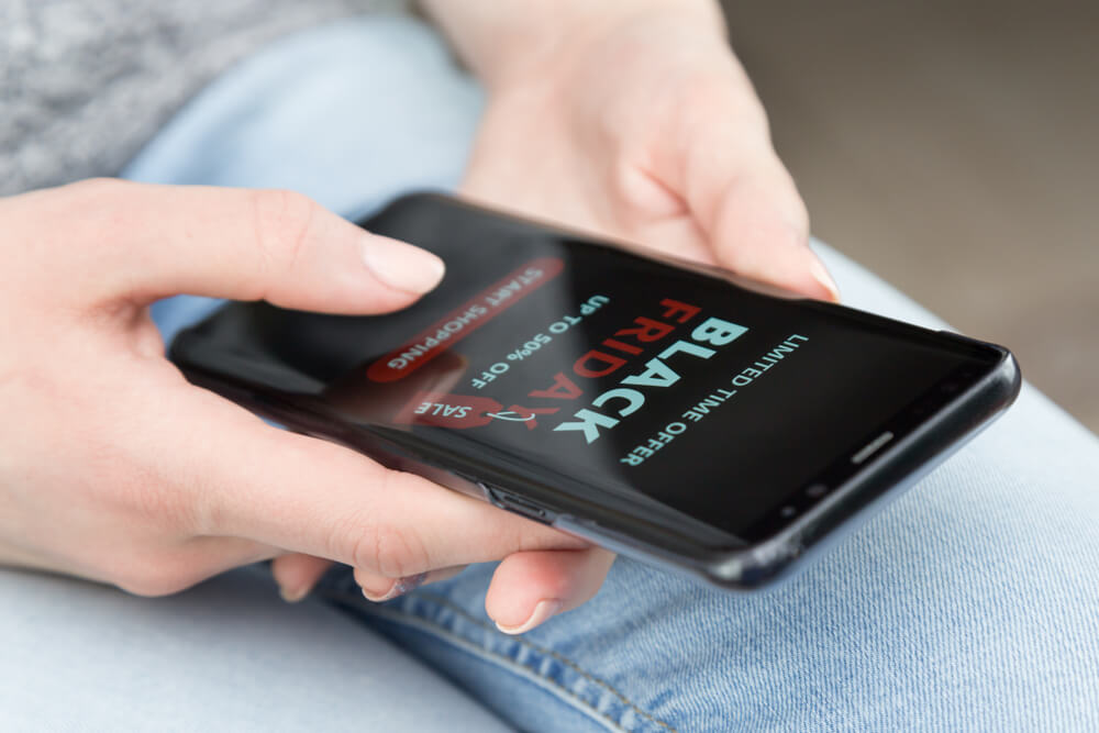 A person holding a a cell phone with a Black Friday ad