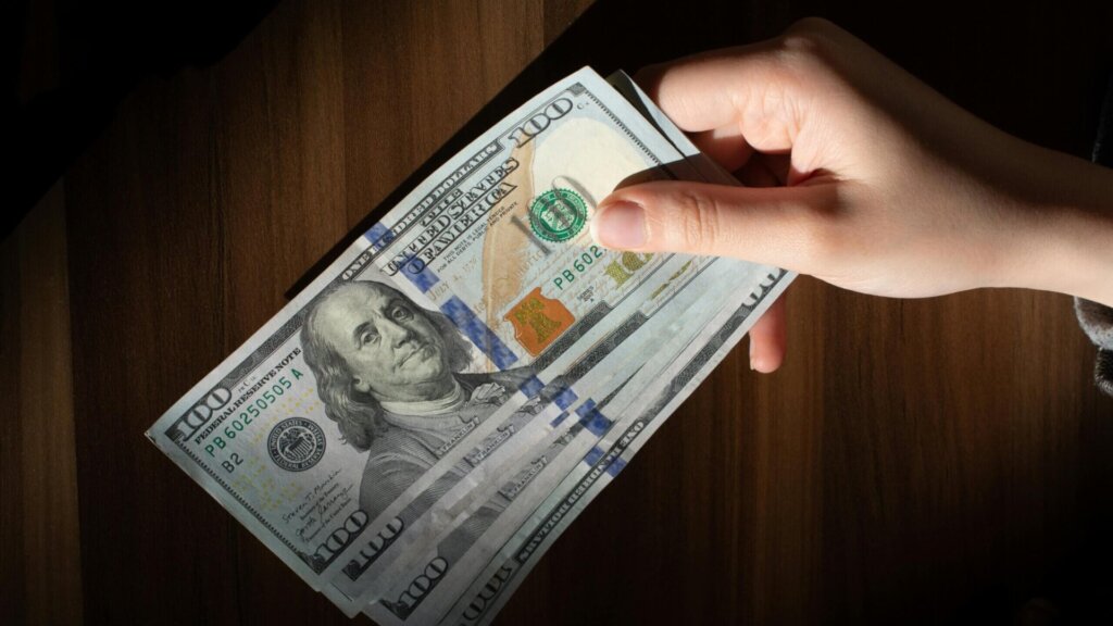 Person holding a stack of banknotes in their hands.