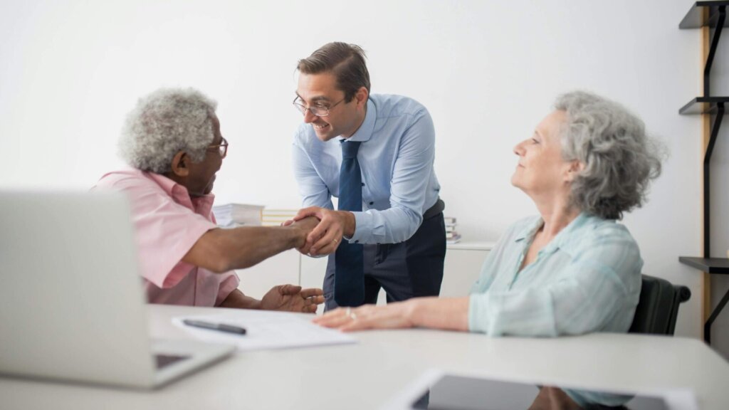 Man in a blue long-sleeve shirt holding the hand of a man in a pink shirt.