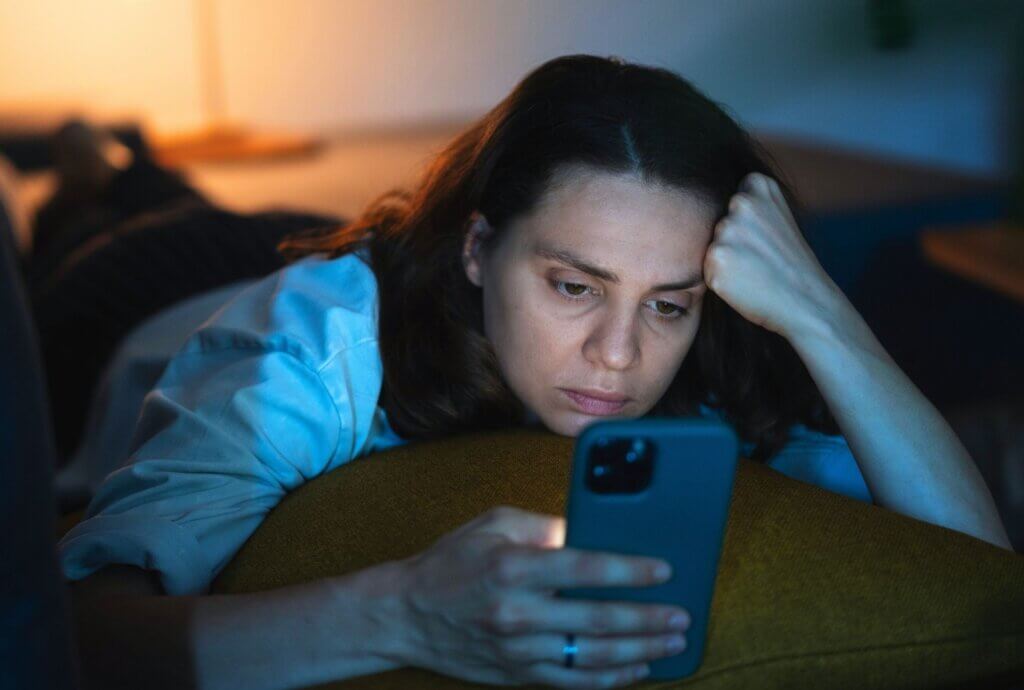 Woman looking at her phone in a dimly lit bedroom