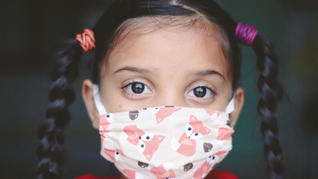 A young girl wearing a mask with print