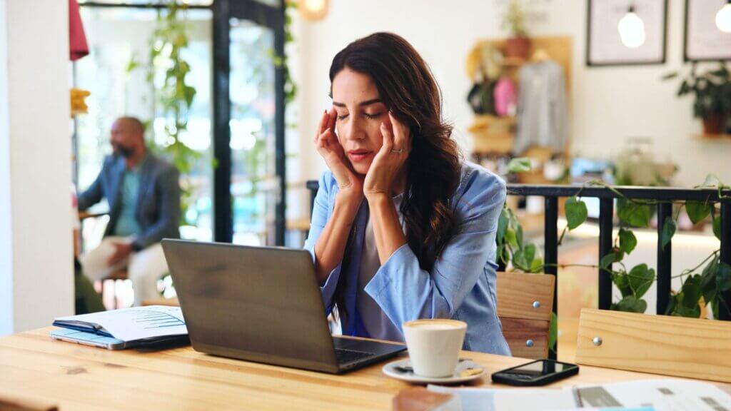 A woman sitting at a desk looking frustrated over a laptop