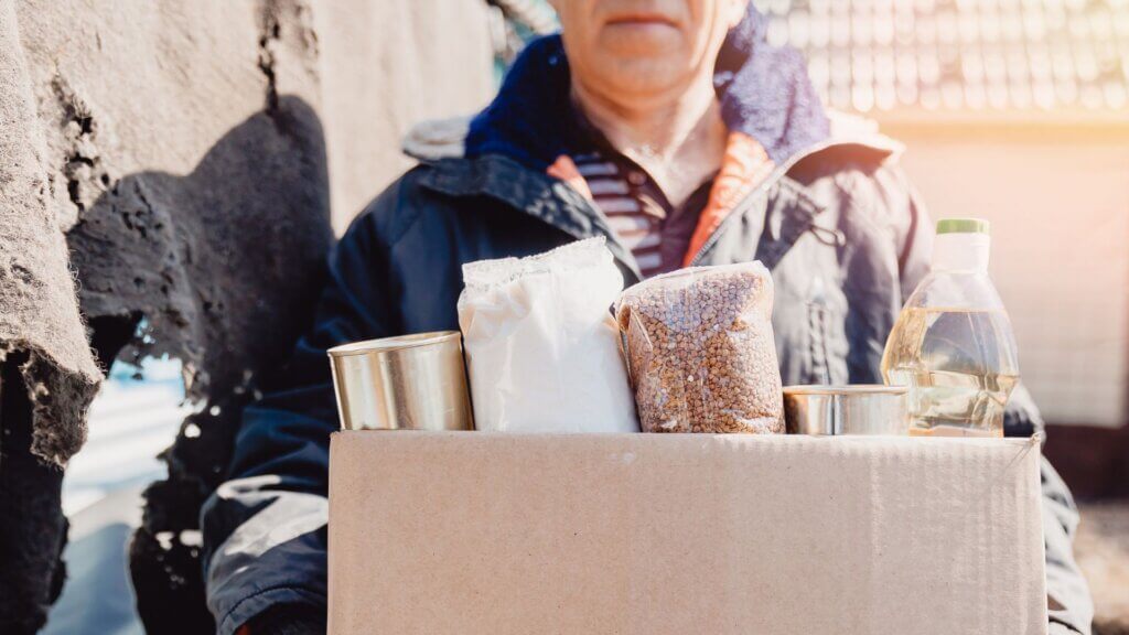 A person in need holding a bin of donated food
