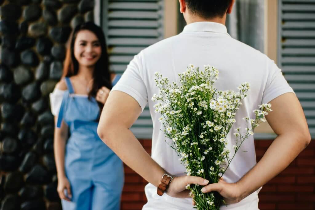 Man holding baby's breath flowers behind his back