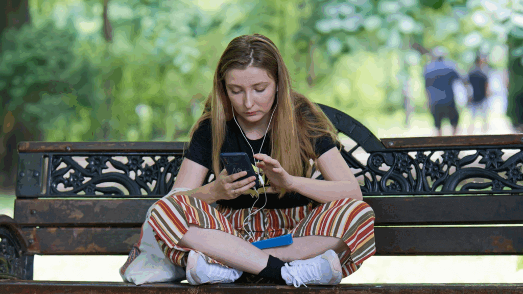 Woman sitting at park bench looking at her phone