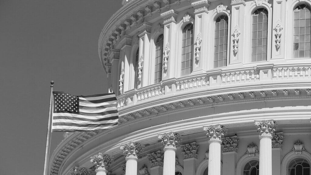Close-up of the U.S. Capitol building with an American flag waving in the foreground.