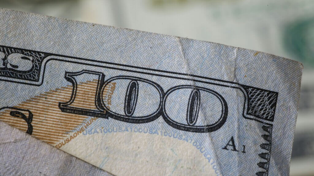 Close-up detail of a $100 bill highlighting paper texture and ink