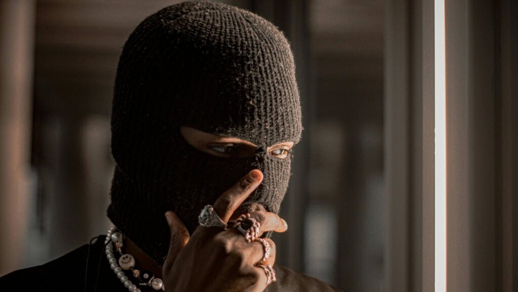 Person wearing a black ski mask, partially obscured, creating a sense of anonymity or caution.