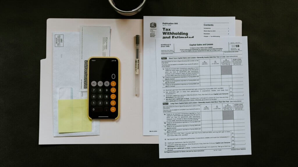 Smartphone and pen resting on tax withholding documents on a desk