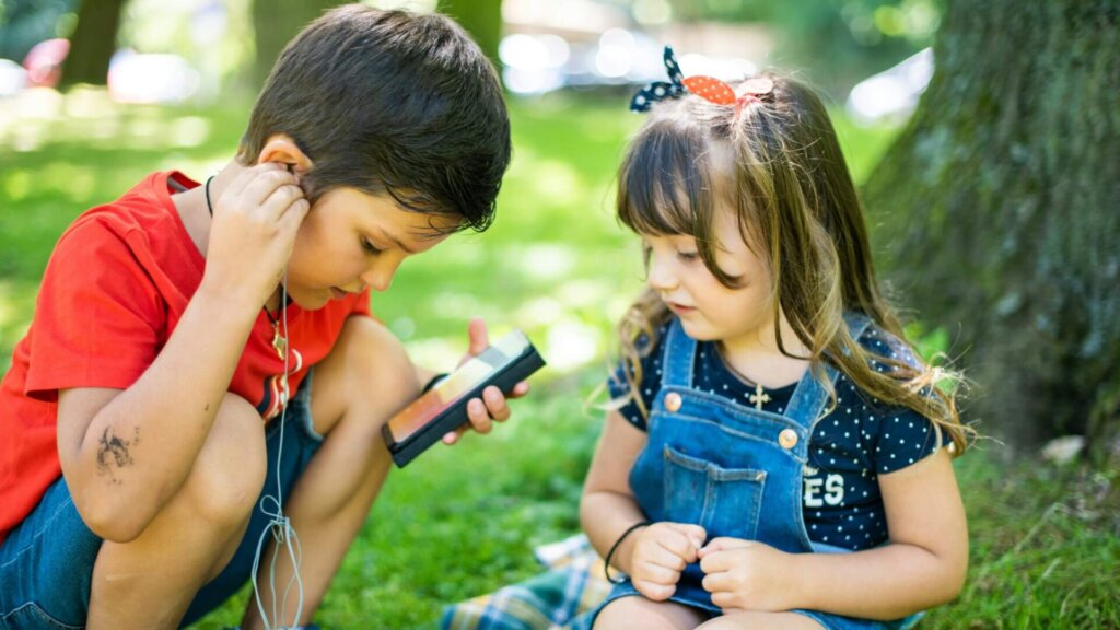 Girl wearing a blue denim vest holding a smartphone.