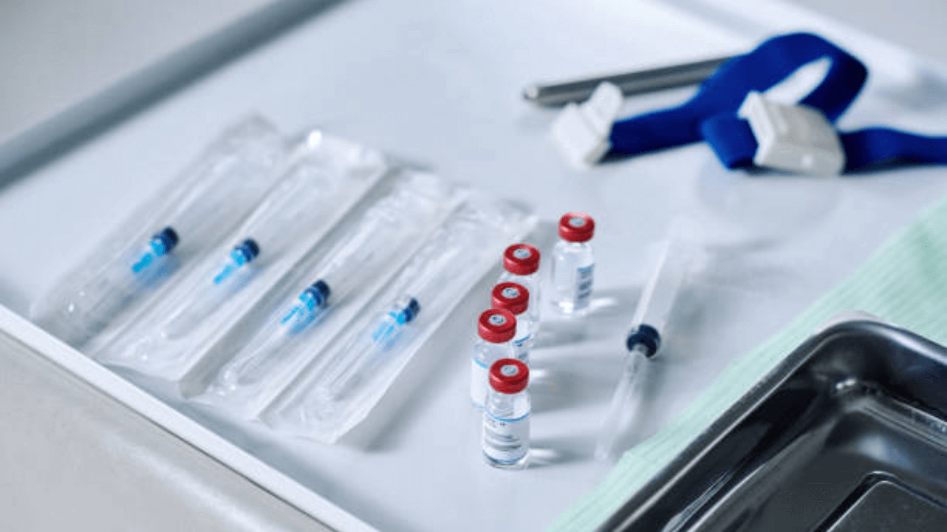 Close-up of medical syringes and vaccine vials on a tray.