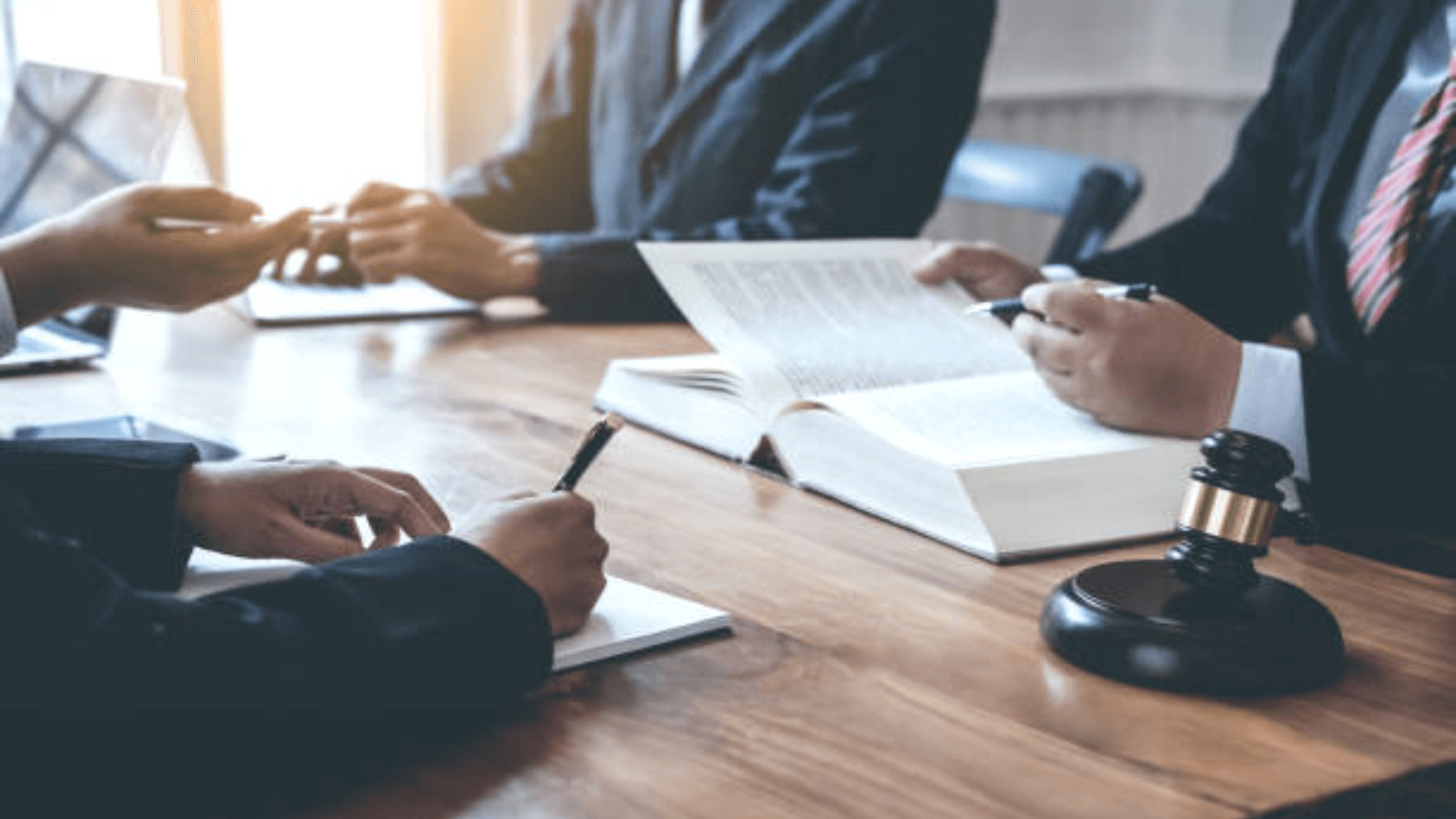 Lawyers in suits having a discussion at a table with legal books and a gavel.