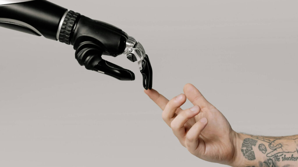 Bionic prosthetic hand and human hand pointing at each other.