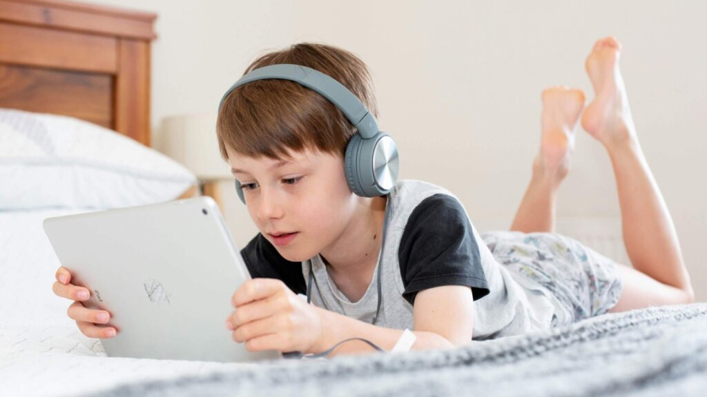 Boy in a black shirt using a white laptop computer.