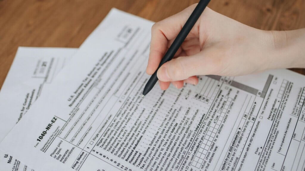 Person filling out tax documents on a desk