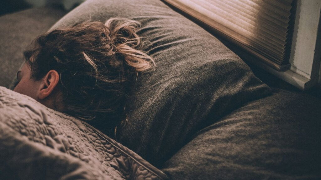 Woman sleeping on a bed covered with blankets.