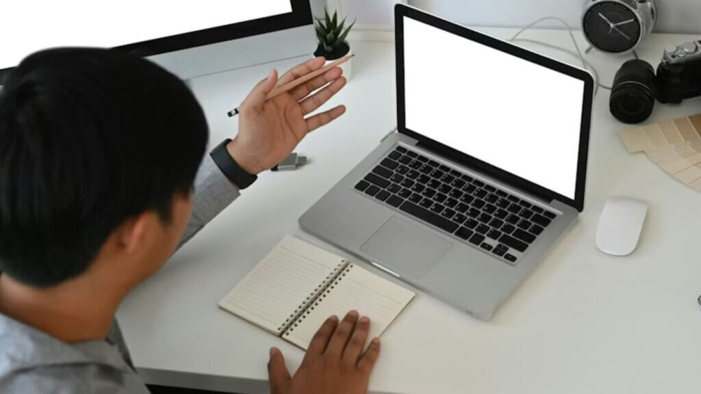 A man sitting with his hand raised at a computer
