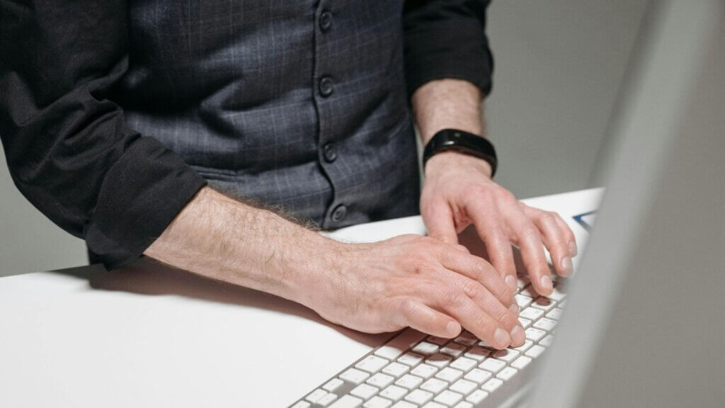 A man standing and typing at a computer keyboard