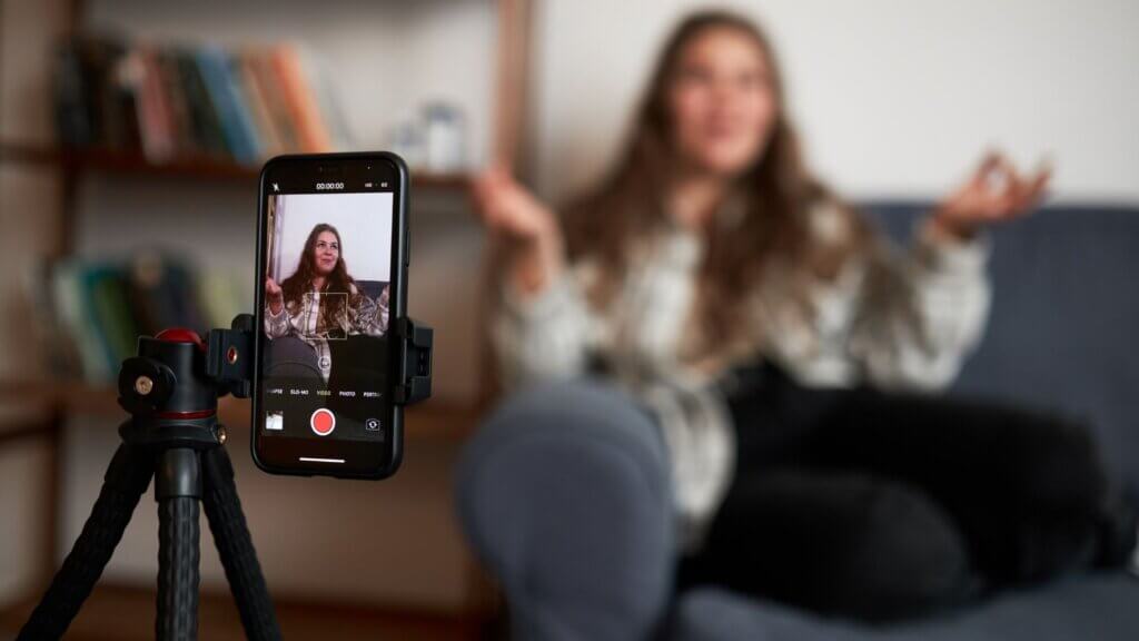A woman speaking and being recorded by a cellphone