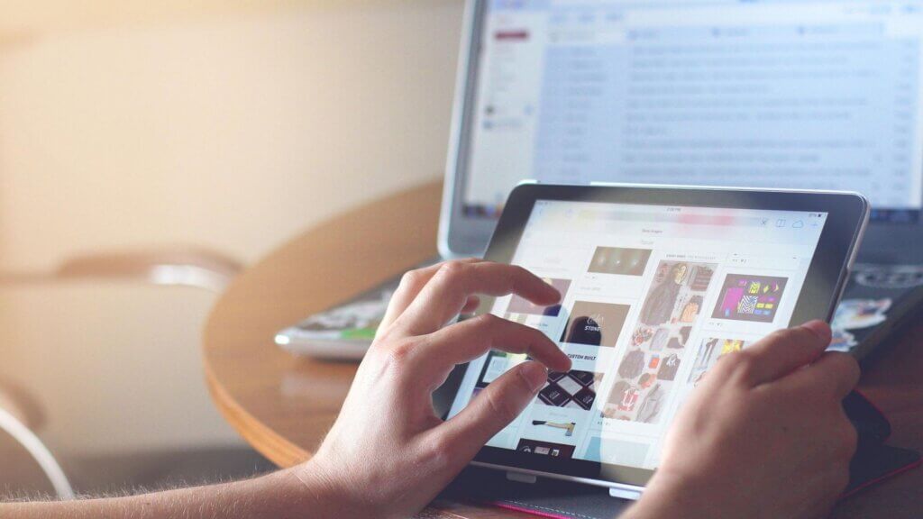 A person using their tablet in front of their computer