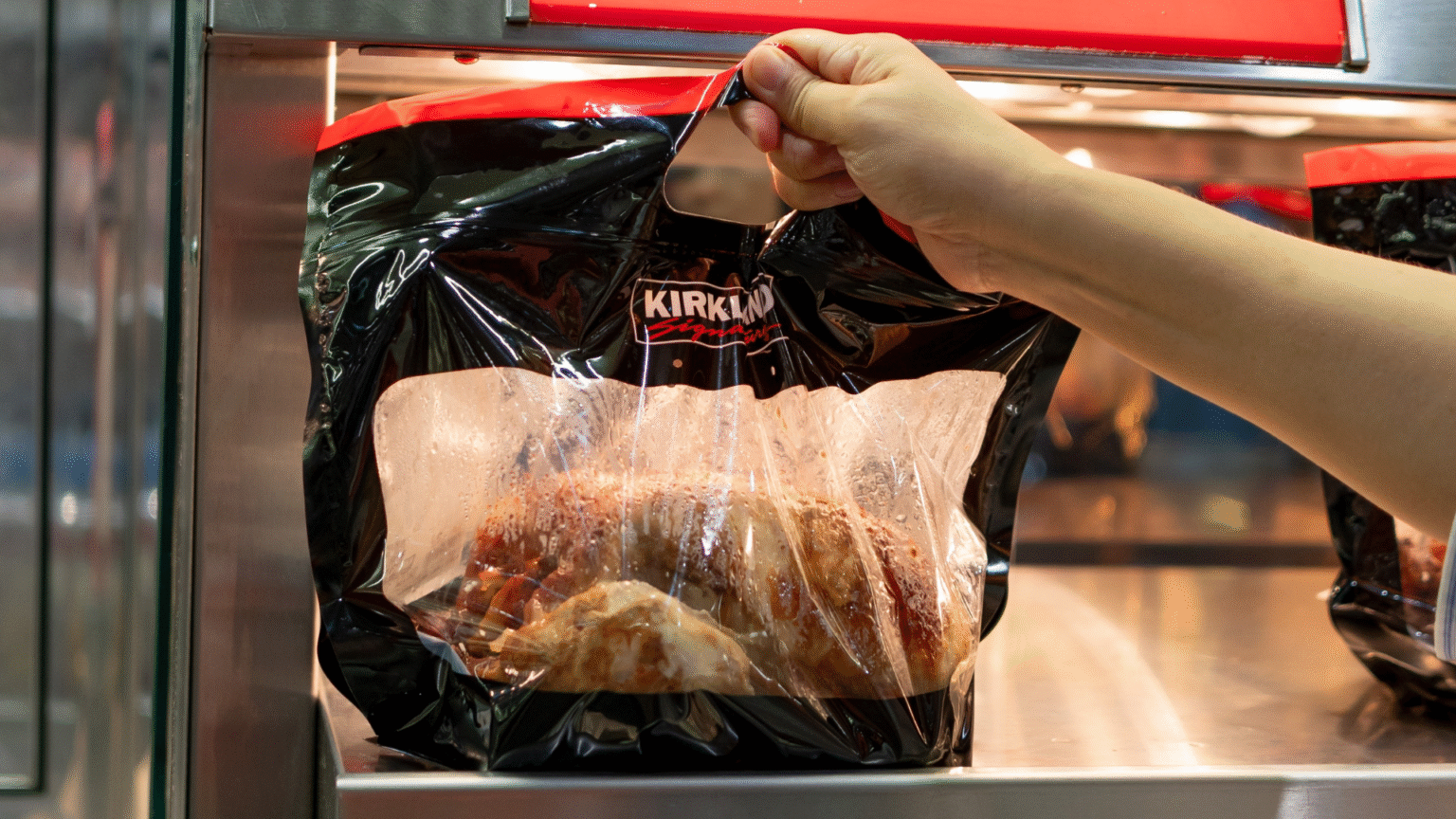 Hand picking up Costco’s $4.99 Rotisserie Chicken