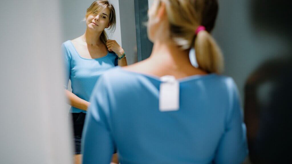 Woman tries on top in mirror in fitting room
