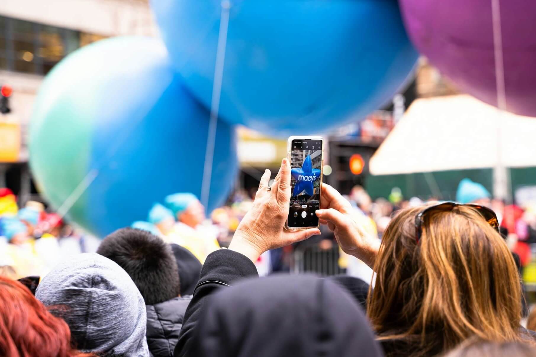 Woman taking a photo of a Macy's balloon