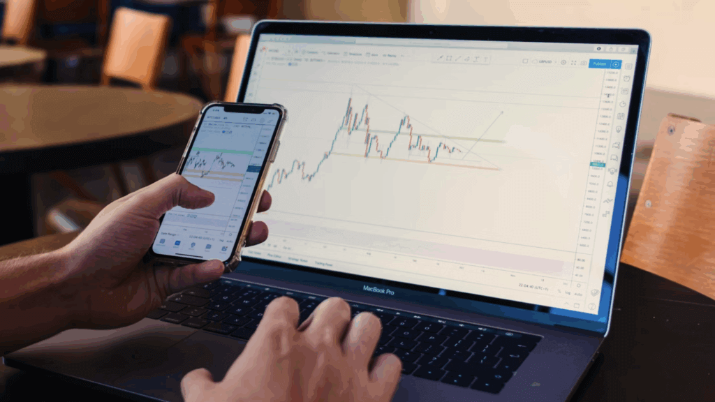 man looking at Stocks on phone and laptop