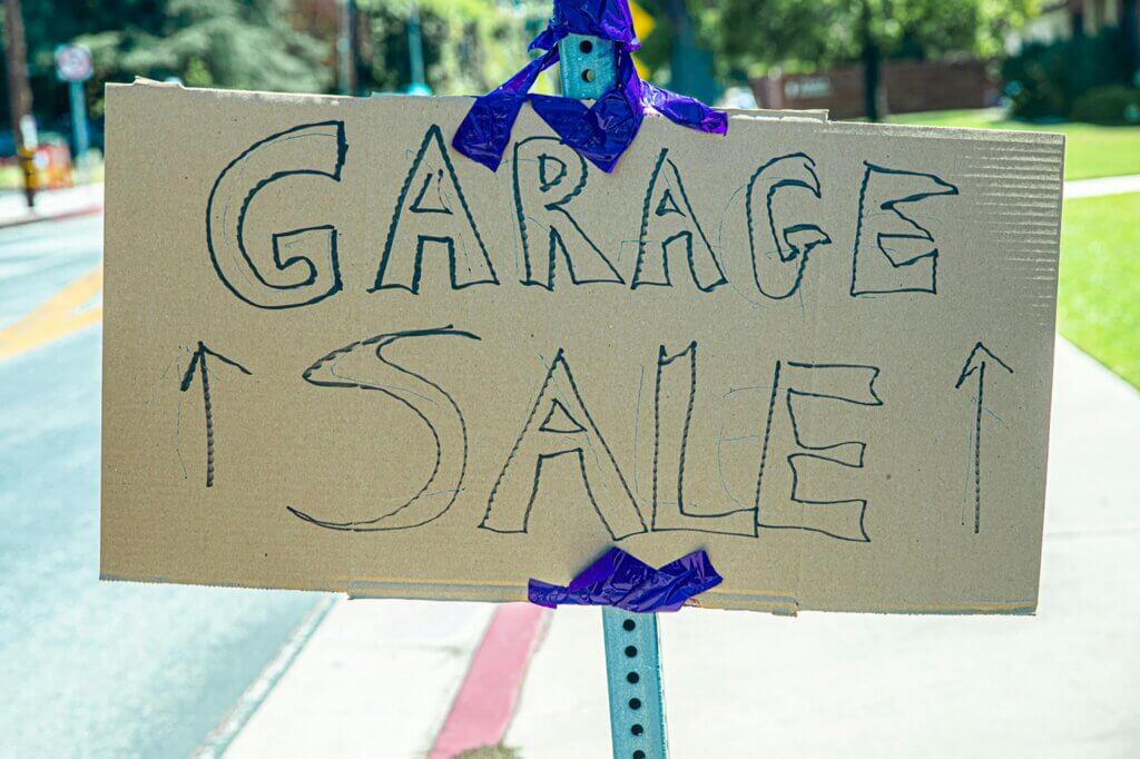 Hand-written garage sale sign at the side of a residential road