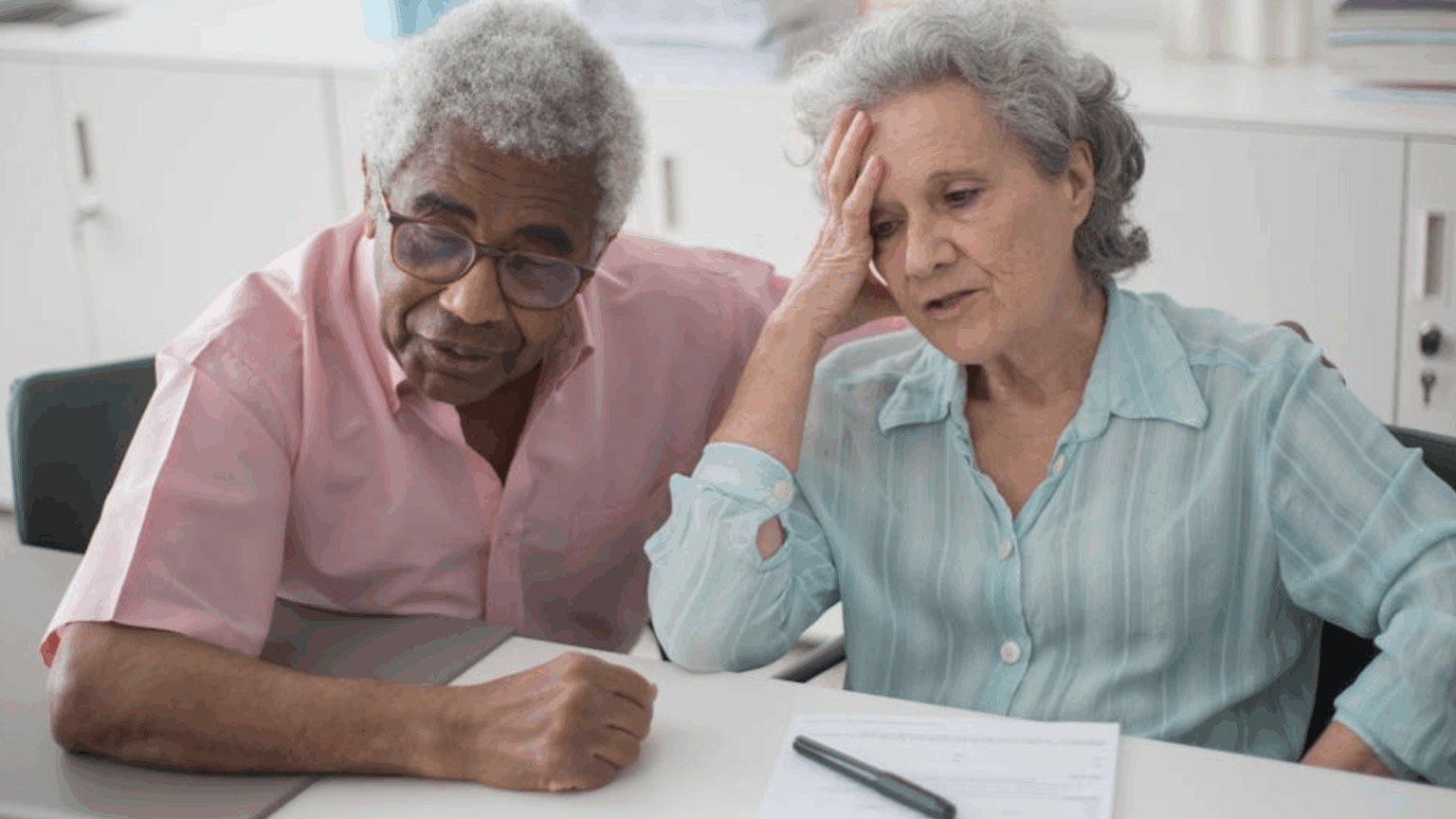 Retirees Question Waiting Until 70 as $50,000 Social Security Cap Proposal Sparks Debate Older couple reviewing paperwork together at a table, appearing concerned about financial matters.